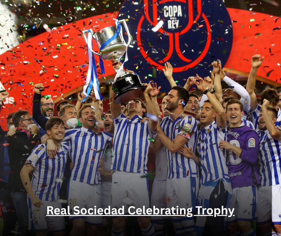 Real Sociedad players lifting the Copa del Rey trophy amid blue and white confetti at Estadio de La Cartuja in Seville